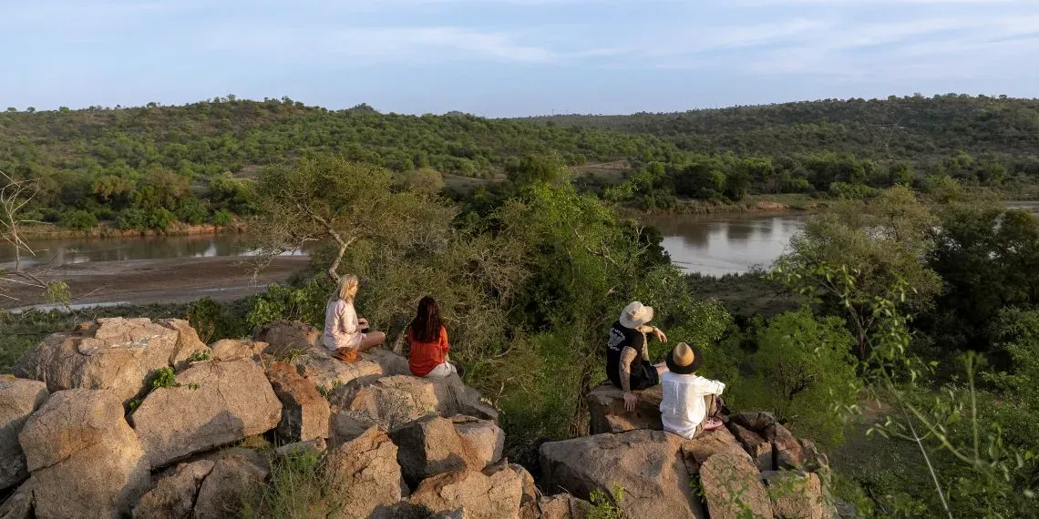 vier mensen zittend op stenen met uitzicht