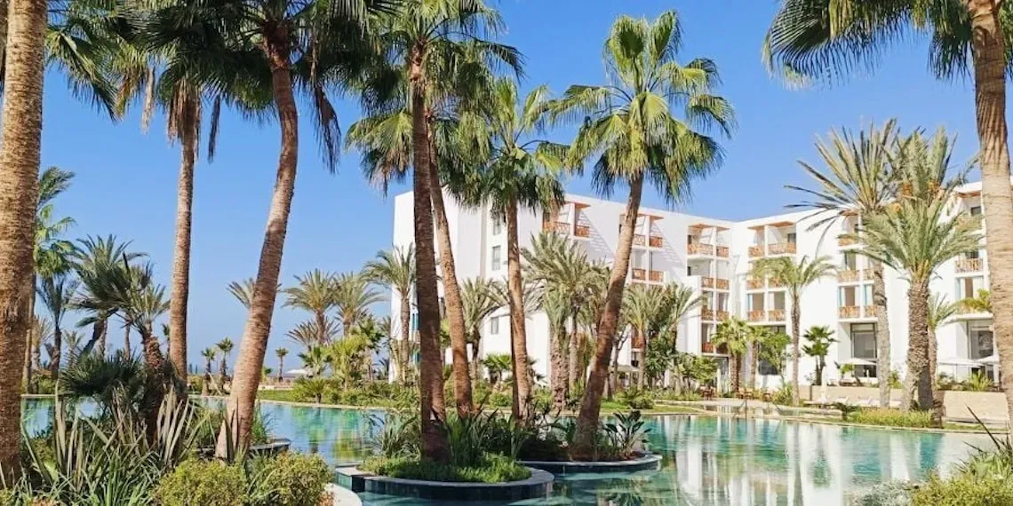 zwembad met palmbomen en hotel